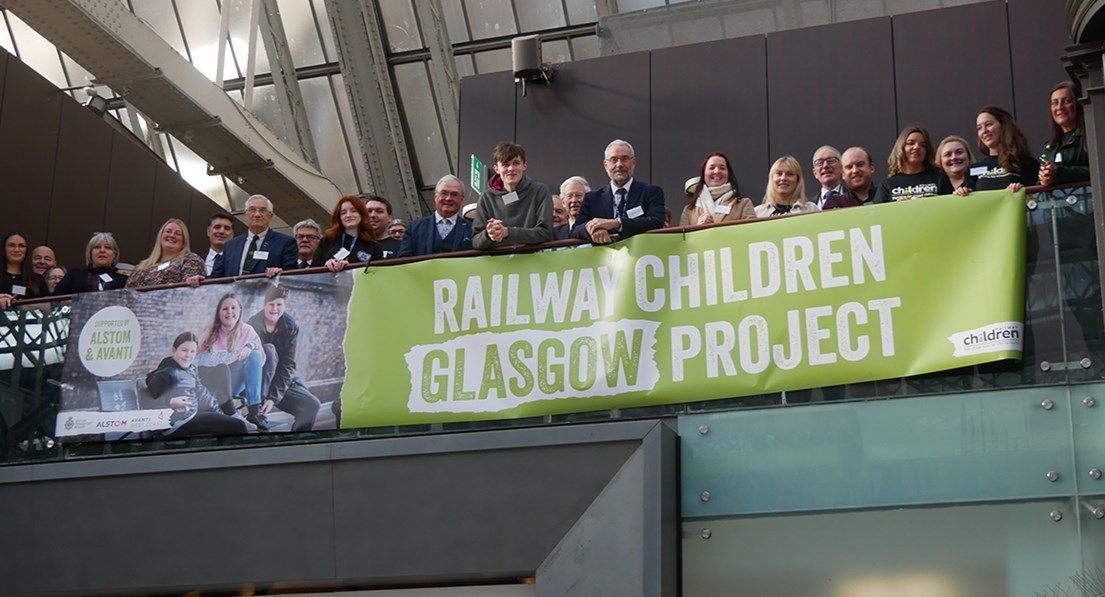 Group of people stood with railway children glasgow banner,