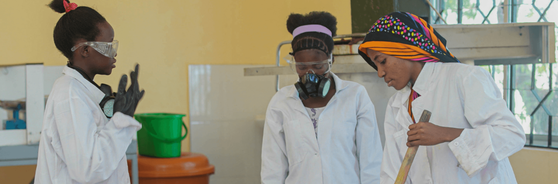 Young women in Tanzania wearing white overcoats and producing soap