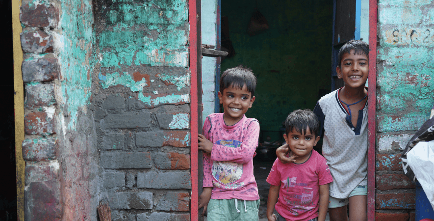 Three children standing in the doorway on the streets of India. Image shows the impact your payroll giving donation could make on the lives of vulnerable children Railway Children works with in India