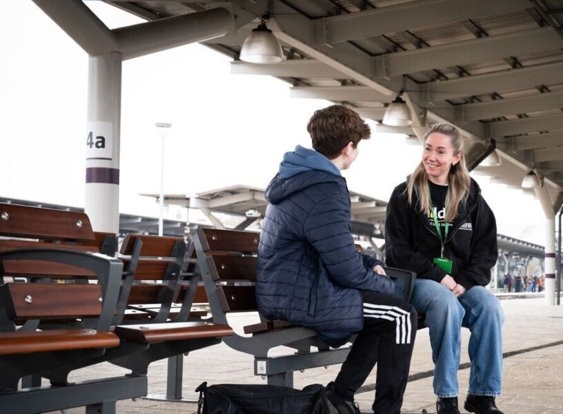 Railway Children worker speaking to child on bench on train platform