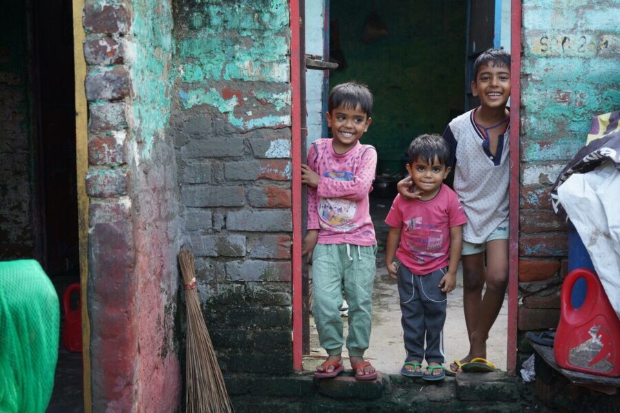 Three children standing in a doorway on the streets of India