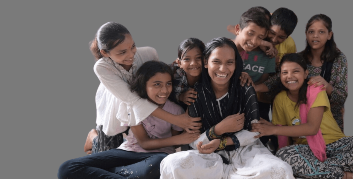 Photo of a Railway Children project worker in India sat on the floor with a group of children.