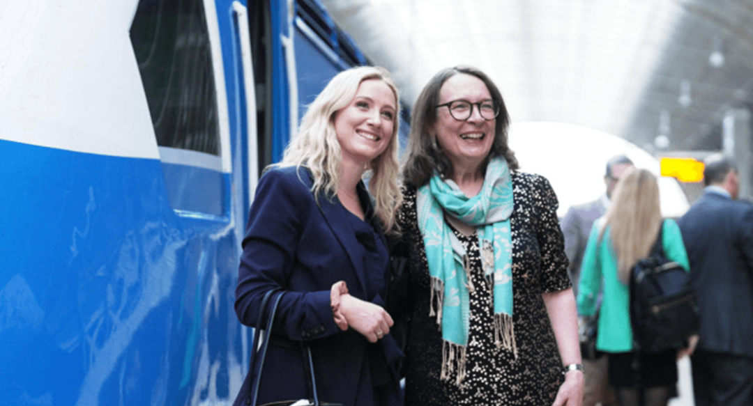 Twp women smiling for the camera - stood by the pullman train.