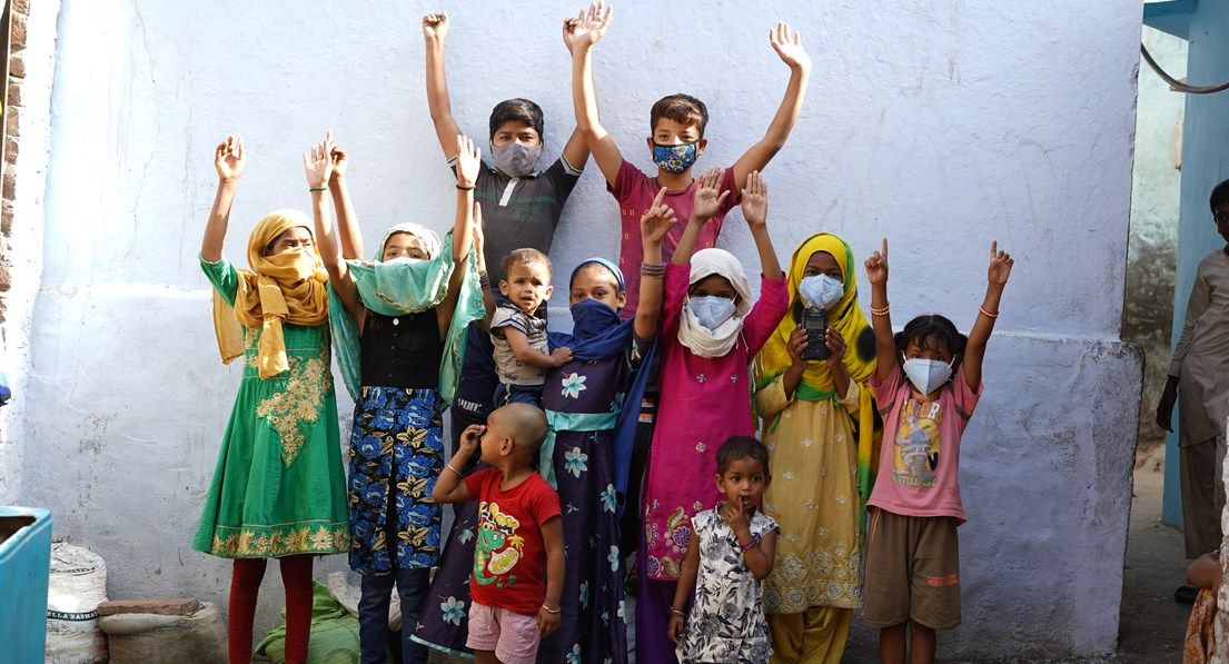 Indian children wearing covid masks raising arms in cheer