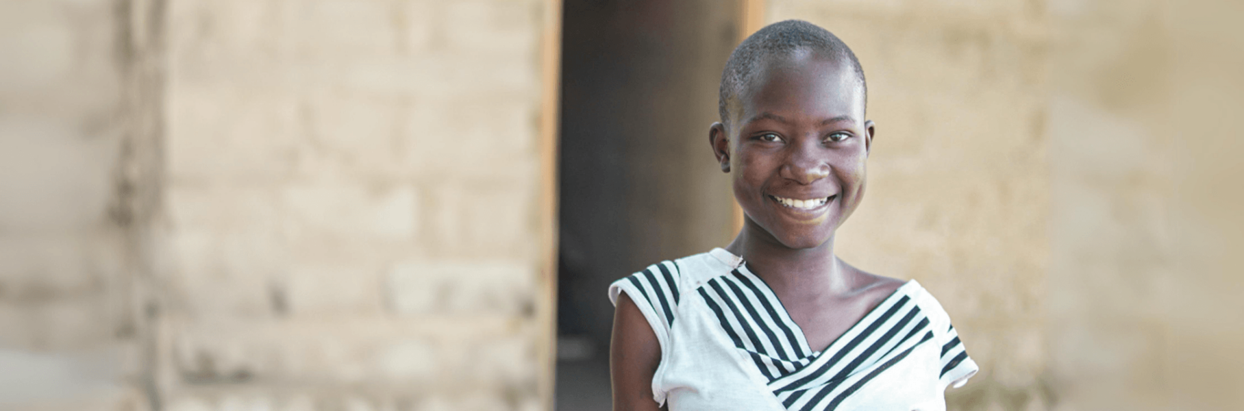 Tanzanian girl in white top smiling at camera