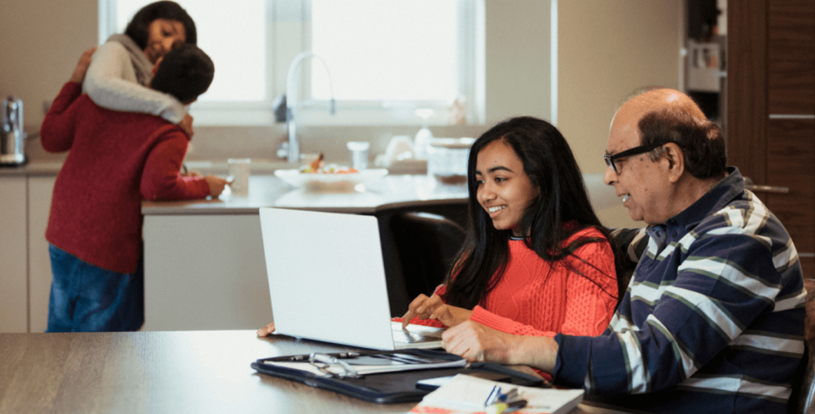 Teenager writing on a laptop being supervised by her father